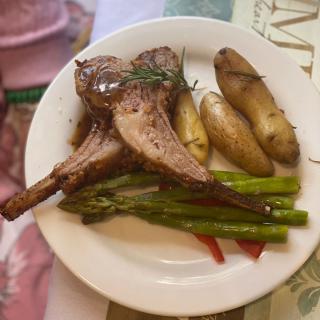 A plate of lamb chops served with fingerling potatoes and asparagus.
