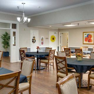 A well-furnished dining area with multiple tables and chairs, decorative artwork, and soft lighting.