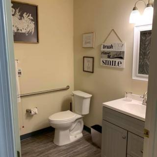 A clean and modern bathroom with a toilet, sink, mirror, and decorative elements on the walls.