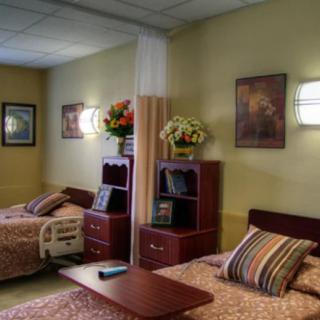 A well-decorated hospital room with two patient beds and floral arrangements.