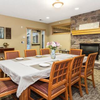 A cozy dining room with a well-set table and a stone fireplace.