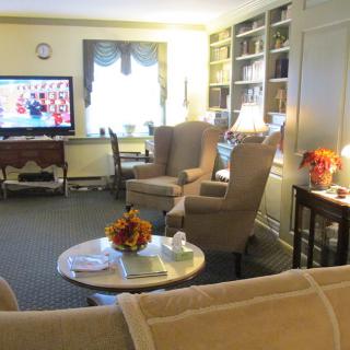 A cozy living room with armchairs, a television, and built-in bookshelves.
