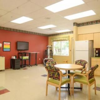 A bright and inviting break room with a table, chairs, television, and kitchen appliances.
