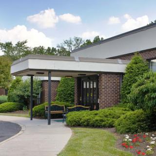 A welcoming entrance to a modern building surrounded by lush greenery.