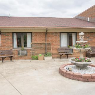 A peaceful courtyard with a fountain and benches outside a residential brick building.