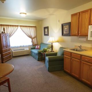 A cozy living room with a couch, kitchenette, and natural light from a large window.
