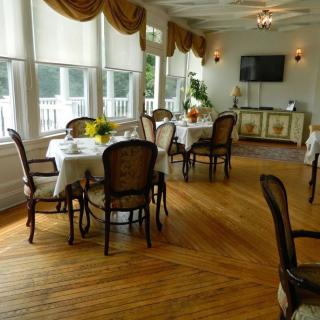 An elegant dining room with tables and chairs, warmly lit by natural sunlight.