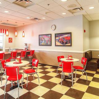 A retro-style diner interior with red chairs and a checkered floor.