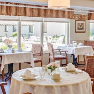 A cozy dining area with neatly arranged tables and chairs, adorned with white tablecloths and floral centerpieces.
