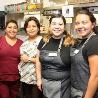 A group of women posing in a kitchen.