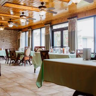 A cozy dining area with neatly arranged tables and chairs, illuminated by natural light.