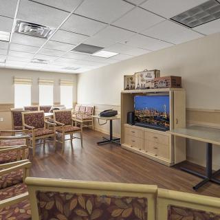 An empty waiting room with patterned chairs and a television.