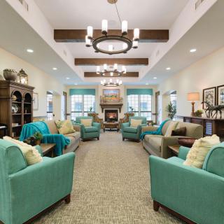 A cozy and inviting living room with teal sofas, a central fireplace, and elegant chandeliers.