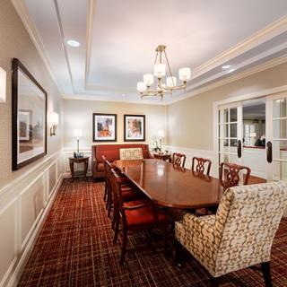 A well-appointed dining room featuring a large wooden table, upholstered chairs, artwork on the walls, and an elegant chandelier.