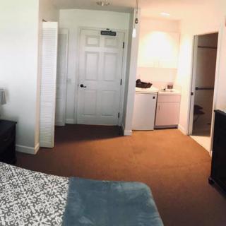 A cozy hotel room with a view of the entrance and a small laundry area.