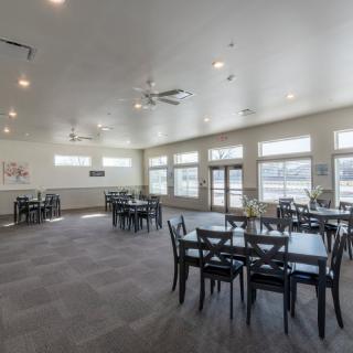 A spacious dining area with multiple tables and chairs, featuring large windows and modern lighting.