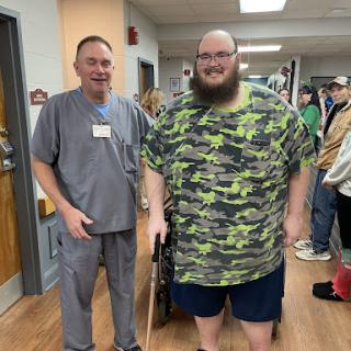 A patient using a walking aid stands alongside a hospital staff member, highlighting the supportive environment in rehabilitation.