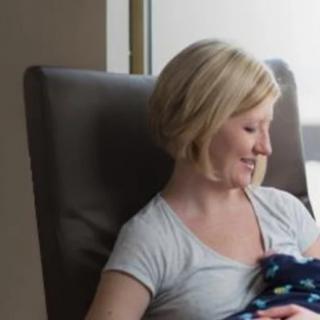A mother nursing her baby in a comfortable chair by the window.