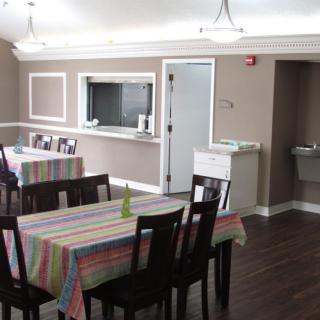 A cozy dining area with tables covered in colorful tablecloths and a view into the kitchen.