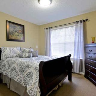A cozy bedroom with a bed, dresser, and large window with curtains.