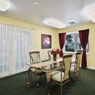 A well-lit dining room with elegant furniture and red curtains.