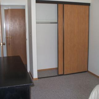 A simple bedroom interior featuring a closet with sliding doors and a desk.