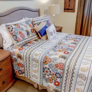 A cozy bedroom featuring a bed with a colorful floral quilt and decorative pillows.