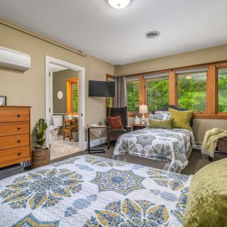 A cozy bedroom featuring twin beds, large windows with a view, and modern decor.
