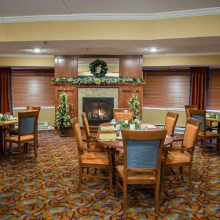 A cozy dining room with a fireplace and decorated with festive accents.
