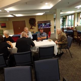 A group of people sitting around a table having a conversation in a dining area.