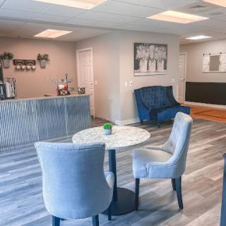 A cozy and modern waiting area featuring stylish blue chairs and a marble table, perfect for relaxation.