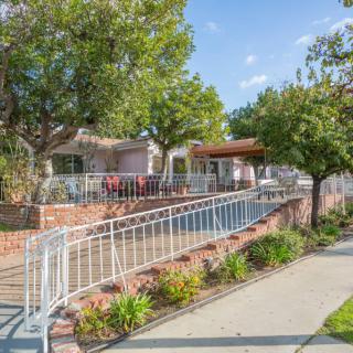 A charming house with a landscaped garden and pathway surrounded by trees.