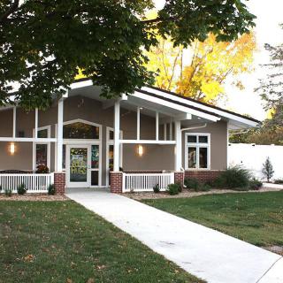 A modern residential house with a front yard and trees lining the entrance pathway.