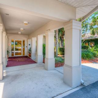 An inviting building entrance with columns and landscaped surroundings.