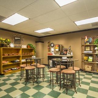 A cozy break room with checkered flooring, tables, chairs, and shelves for storage and decor.