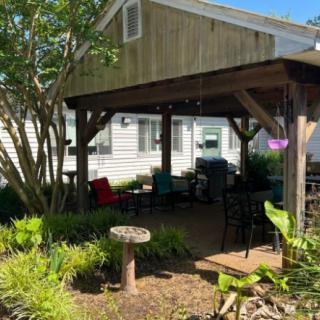 A cozy outdoor patio area with seating, surrounded by lush garden plants.