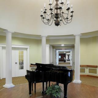 A beautifully designed lobby featuring a grand piano and an elegant chandelier, accentuated by classic columns.
