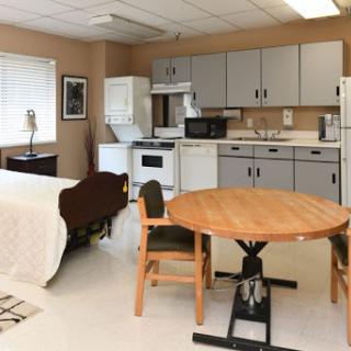 A cozy studio apartment featuring a kitchen, dining table, and a comfortable sleeping area.
