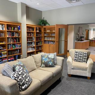 A cozy library reading area with bookshelves, a sofa, and an armchair.