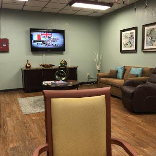A cozy waiting room featuring comfortable seating, a TV, and decorative artwork.