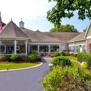 A charming building with a landscaped garden and an American flag in the foreground on a sunny day.