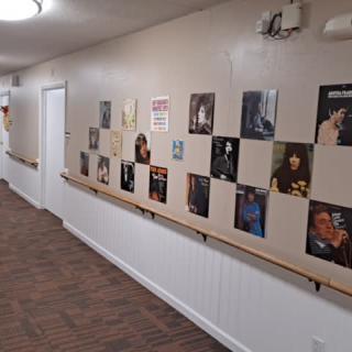 A hallway featuring an art display with various posters and portraits lining the wall.