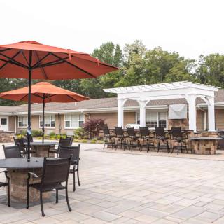 An outdoor patio area with tables, chairs, and umbrellas under a clear sky.