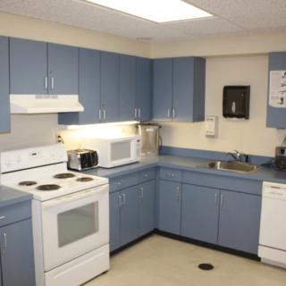 A modern kitchen with blue cabinets and various appliances.
