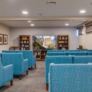 A small theater room with blue upholstered seating and a television at the front.