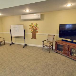 A cozy meeting room featuring a television, whiteboard, and seating area.
