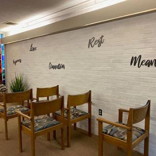 A tranquil waiting area featuring wooden chairs and inspirational words on the wall.