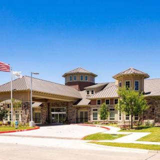 A modern building entrance with landscaping and a flag on a sunny day.