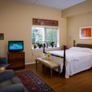 A cozy bedroom with a comfortable bed, a television, and a window with natural light.