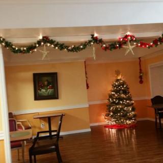 A warmly decorated room with a Christmas tree and festive garlands hanging from the ceiling.
